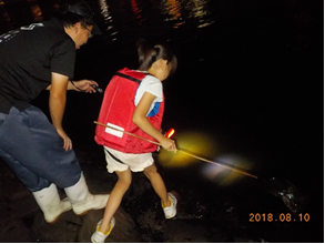 懐中電灯を湖面にあててエビを探す様子です